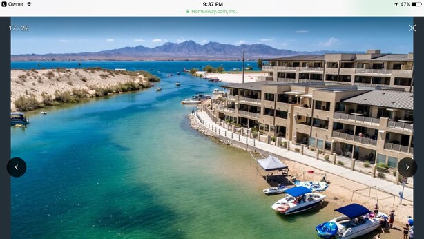 A coastal hotel with a marina, clear blue waters, and mountains in the background.