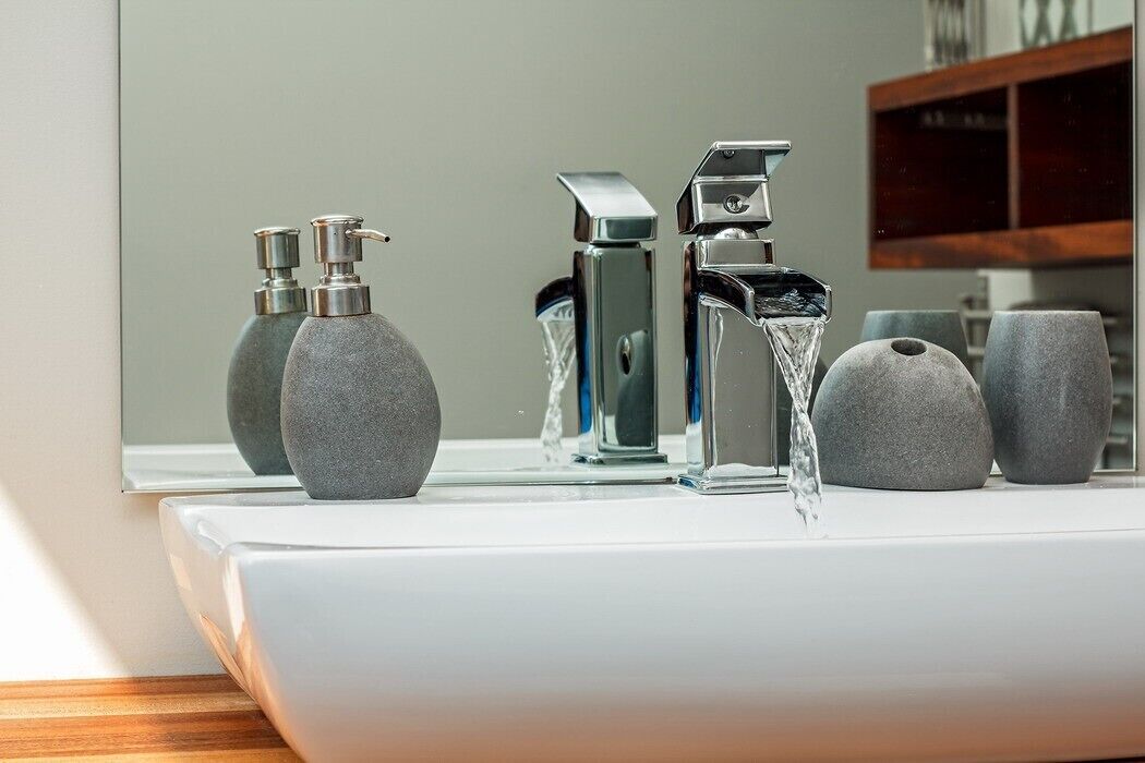 Ein Waschtisch mit modernem Wasserhahn und Seifenspendern.