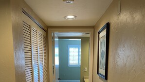 A hallway with a door leading to a bathroom, a window, and a picture on the wall.