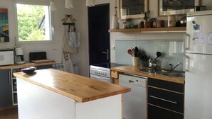 Une cuisine avec un îlot central en bois, des armoires blanches, une cuisinière et un réfrigérateur.