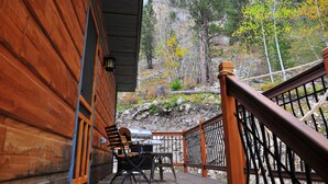 A wooden cabin with a deck, a grill, and a view of rocky terrain and trees. - Spearfish canyon vacation home 15 minutes from Terry Peak Ski Area & Deadwood. (Lead)