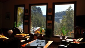 A cozy living room with a large window offering a view of a forested mountain. - Spearfish canyon vacation home 15 minutes from Terry Peak Ski Area & Deadwood. (Lead)