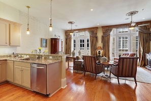 A spacious kitchen with a central island, wooden flooring, and a dining area with striped chairs.