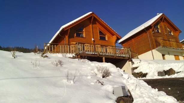 Una cabaña de madera con balcón, rodeada de nieve.