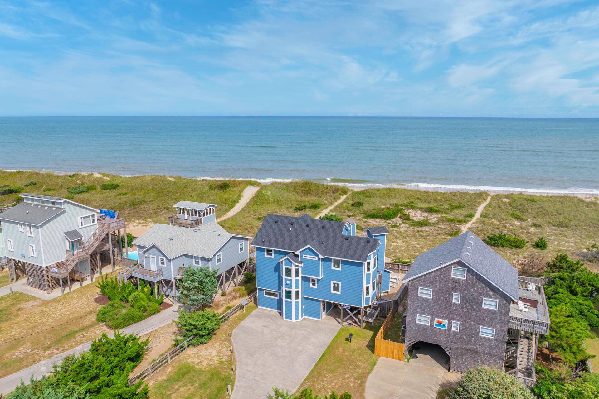 Une propriété située sur la côte, comprenant plusieurs maisons, un sentier menant à la plage et offrant une vue sur l’océan.