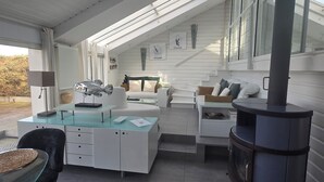 A modern, open-plan living area with a skylight, a fireplace, and a dining area with a glass table. - Waterfront house, large terrace and waterfront - Balcony on Arromanches (Asnelles)