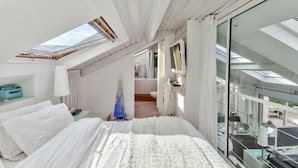 A modern hotel room with a skylight, a bed, a desk, and a view of the balcony. - Waterfront house, large terrace and waterfront - Balcony on Arromanches (Asnelles)