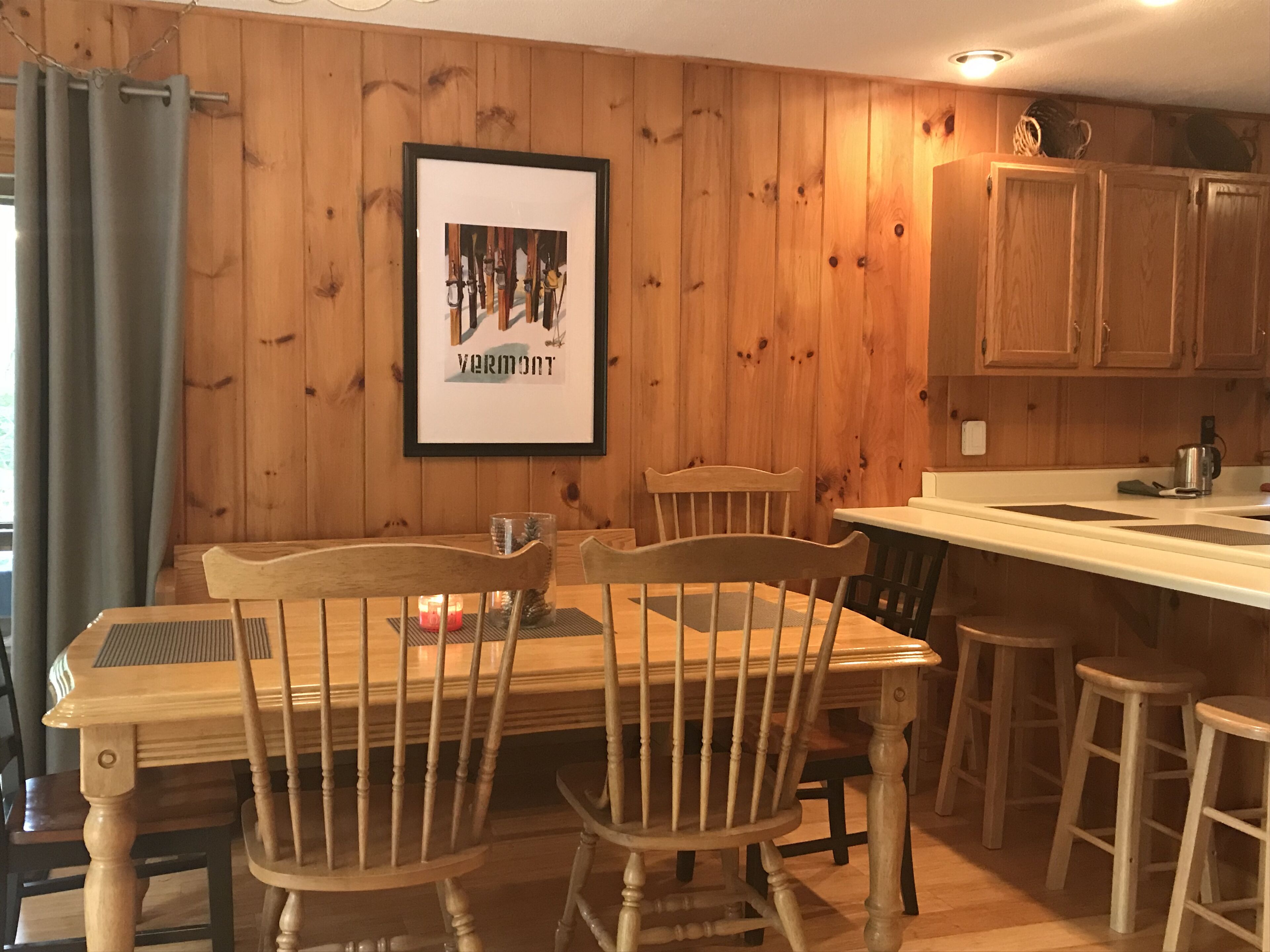 A wooden-paneled room with a dining table, chairs, and a framed picture on the wall.