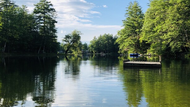 Une rivière paisible, avec un quai et des arbres de chaque côté.