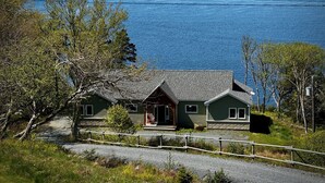 Ett hus med en veranda, en liten terrass och utsikt över en stor sjö eller ett hav.