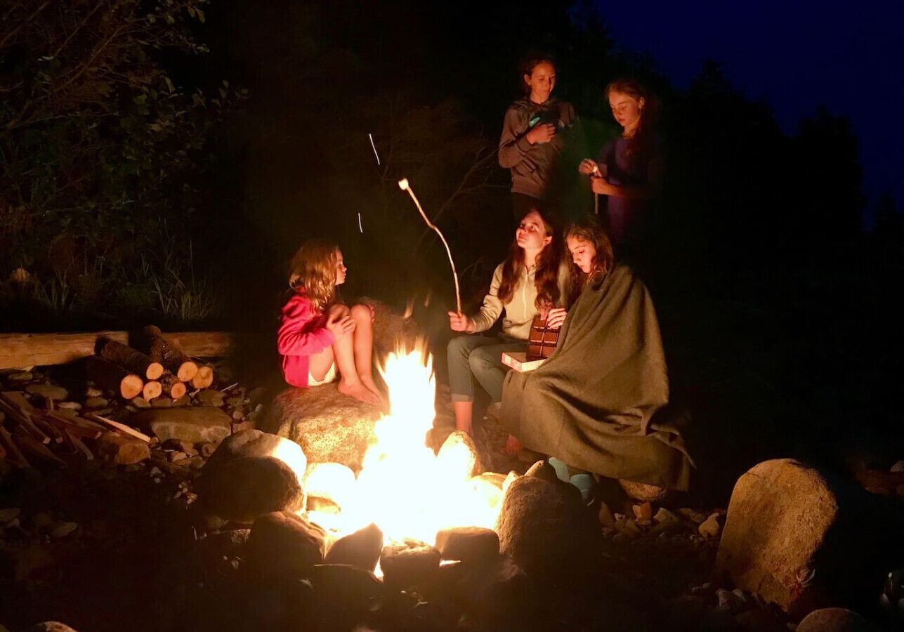 Een groep mensen verzameld rond een kampvuur in de nacht.