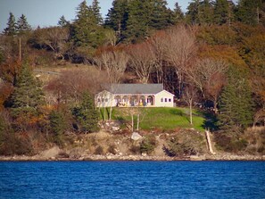 A house with a porch, surrounded by trees and a body of water. - Whitecaps Retreat Beach House (Riverport)