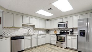 A modern kitchen with white cabinets, stainless steel appliances, and a tiled backsplash. - End of Year Special Unit #413 Rates-Beachfront Beautifully Renovated  2/2Sleeps8 (Orange Beach)