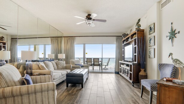 A spacious living room with a large window, a ceiling fan, and a wooden floor. - End of Year Special Unit #413 Rates-Beachfront Beautifully Renovated  2/2Sleeps8 (Orange Beach)