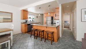 Uma cozinha moderna com ilha central, armários de madeira e área de jantar com mesa e cadeiras.