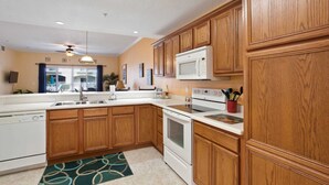 A kitchen with wooden cabinets, a microwave, a stove, and a sink. - Villas of Ocean Gate #106 Ocean side 2 bedroom, pool view, pet friendly (St Augustine)
