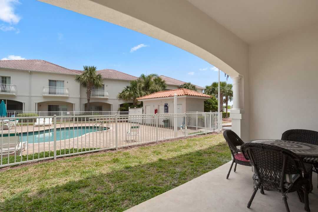 A balcony with a pool, outdoor furniture, and a view of a building with a tiled roof.