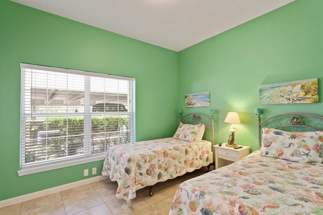 Een slaapkamer met twee bedden, een raam en kunstwerken aan de muur.