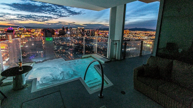A high-rise room with a city view, a glass-enclosed jacuzzi, and a modern interior design.