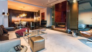 A modern living room with a glass coffee table, leather sofa, and a fireplace.