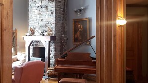 Un salon chaleureux avec un grand piano, une cheminée et un mur en pierre.