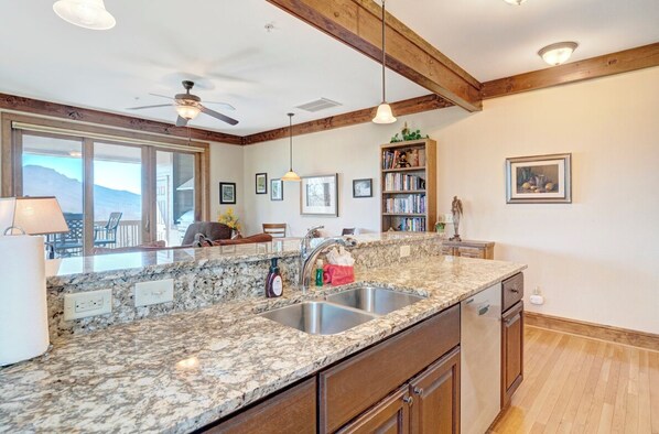 A kitchen with granite countertops, a double sink, wooden cabinets, and a ceiling fan. - Chalakee Lodge CB-1- Mountain View, Gated Resort, Indoor/Outdoor Pools & Hot Tub (Boone)