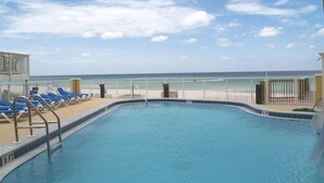 A pool with a 5 ft depth marker, surrounded by blue lounge chairs and a white fence. - Luxury Ocean Front End Unit. Unobstructed sunset views! Beach service included! (Panama City Beach)
