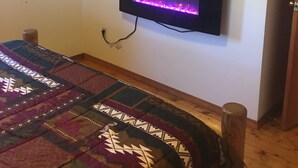 A room with a bed, a wall-mounted TV, and a mirror. - Beautiful, secluded cabin in the hills of the Ozarks. (birch tree)