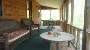 A wooden cabin with a porch, wicker furniture, and a round table with a vase. - Beautiful, secluded cabin in the hills of the Ozarks. (birch tree)