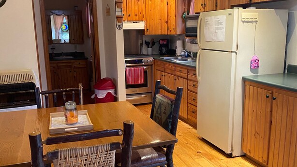 A wooden kitchen with a dining table, chairs, and a refrigerator. - Beautiful, secluded cabin in the hills of the Ozarks. (birch tree)