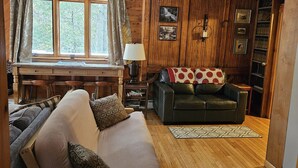 Une pièce chaleureuse avec un plancher en bois, un canapé, un bureau et une bibliothèque.