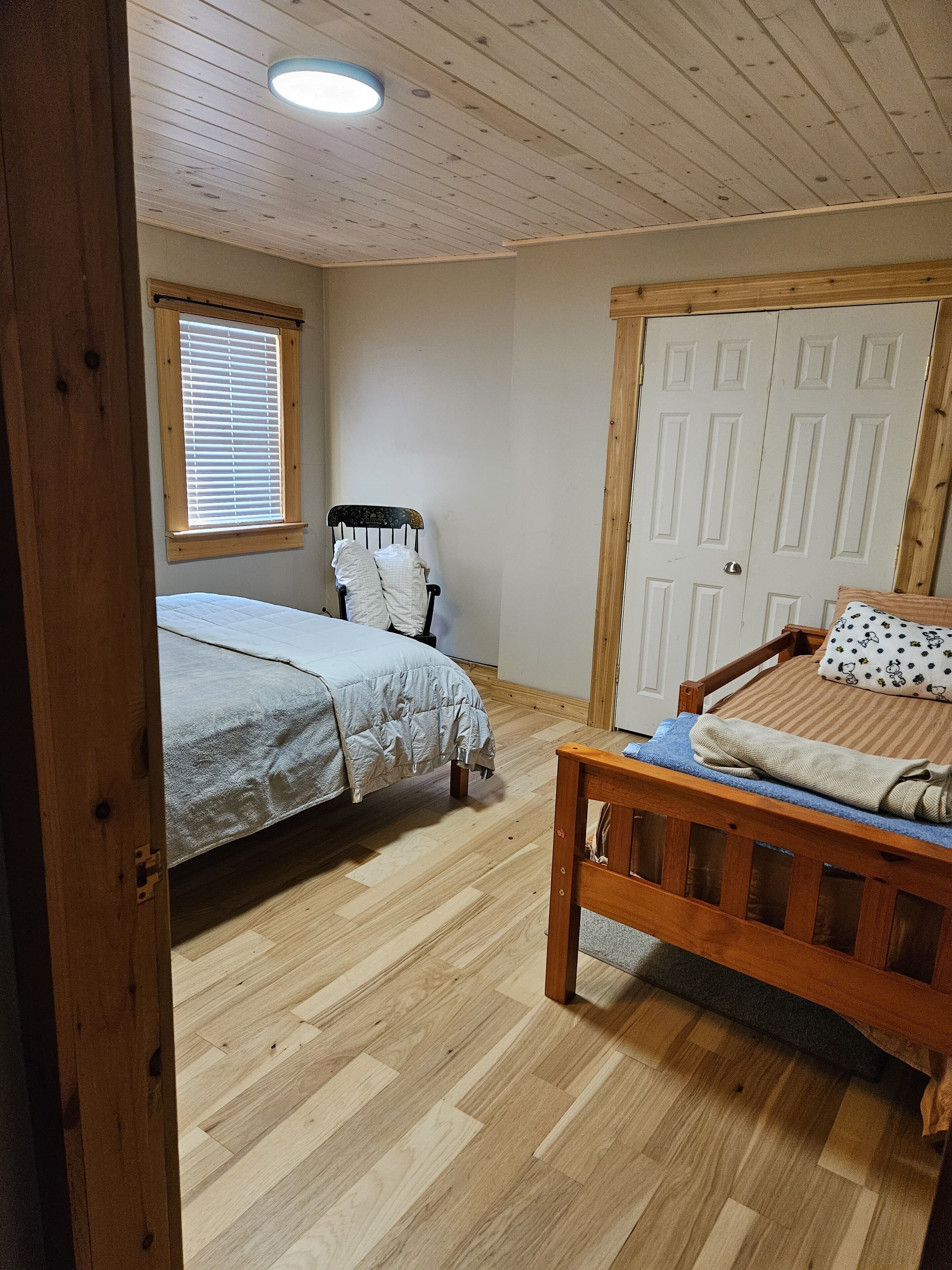 A bedroom with two beds, a wooden door, and a window with blinds.