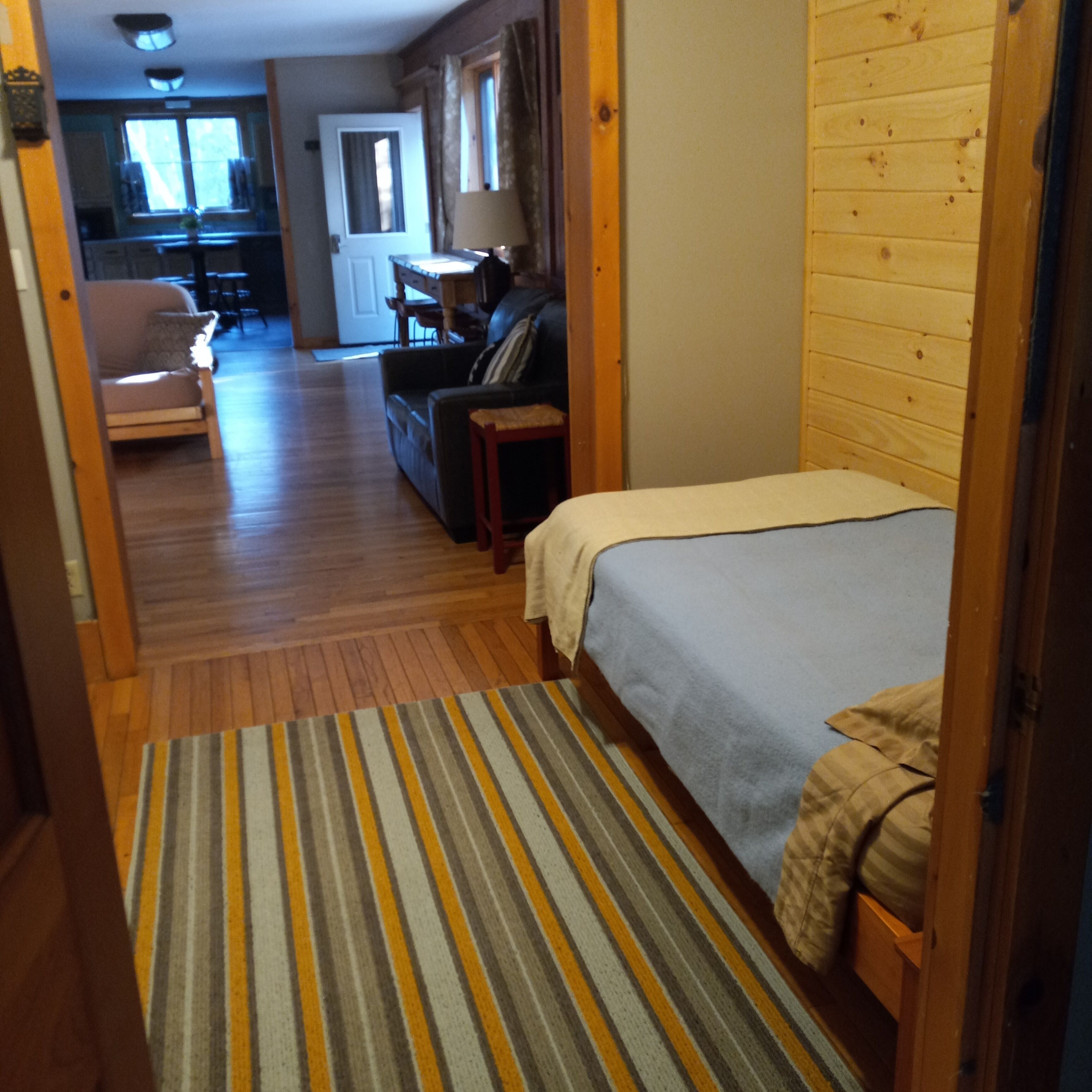 Un couloir étroit mène à une chambre qui comprend un lit, un canapé et, au fond, un coin repas.