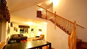 Un salon avec un escalier en bois, un canapé, une table basse et une table à manger.