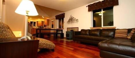 A living room with a sofa, a patterned armchair, a lamp, and a wooden coffee table.