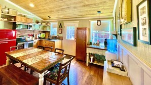 A kitchen with wooden cabinets, a red refrigerator, and a dining table with chairs. - Prime Location in Dripping Springs! Gorgeous Country Cottage for 10 by Camp Lucy (Dripping Springs)