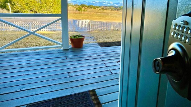 A wooden deck with a view of a fenced field and distant hills. - Prime Location in Dripping Springs! Gorgeous Country Cottage for 10 by Camp Lucy (Dripping Springs)