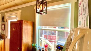 A kitchen area with a wooden ceiling, a hanging light fixture, a window with blinds, and a countertop with kitchen items. - Prime Location in Dripping Springs! Gorgeous Country Cottage for 10 by Camp Lucy (Dripping Springs)