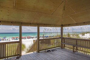 Un pavillon de plage en bois offrant une vue sur la plage et l’océan.