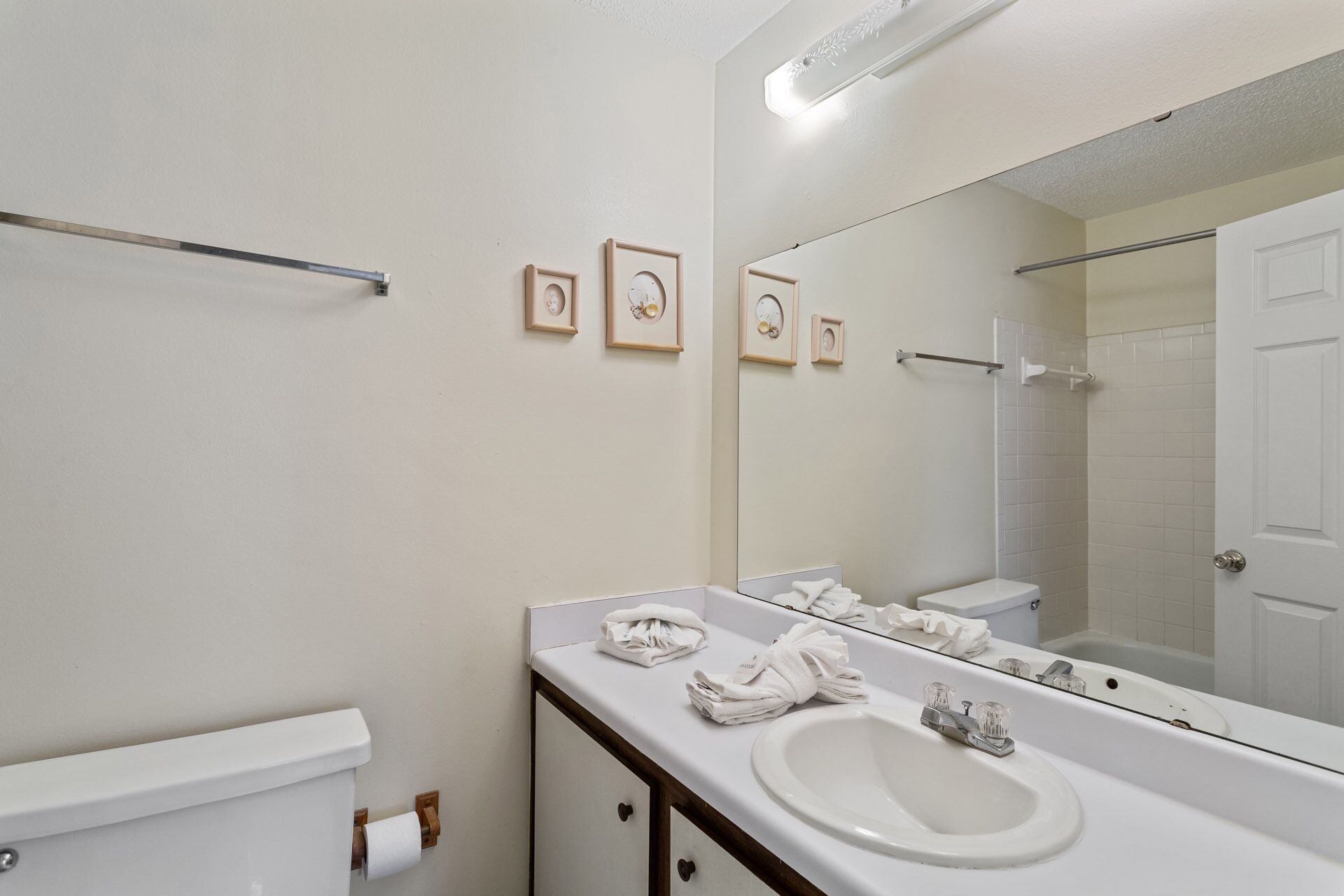 A bathroom with a white sink, a toilet, a mirror, and a towel rack.