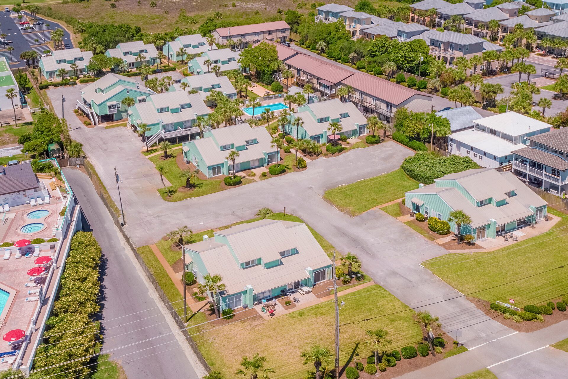 Un quartier résidentiel composé de plusieurs maisons à deux étages, d’une piscine et d’un court de tennis.