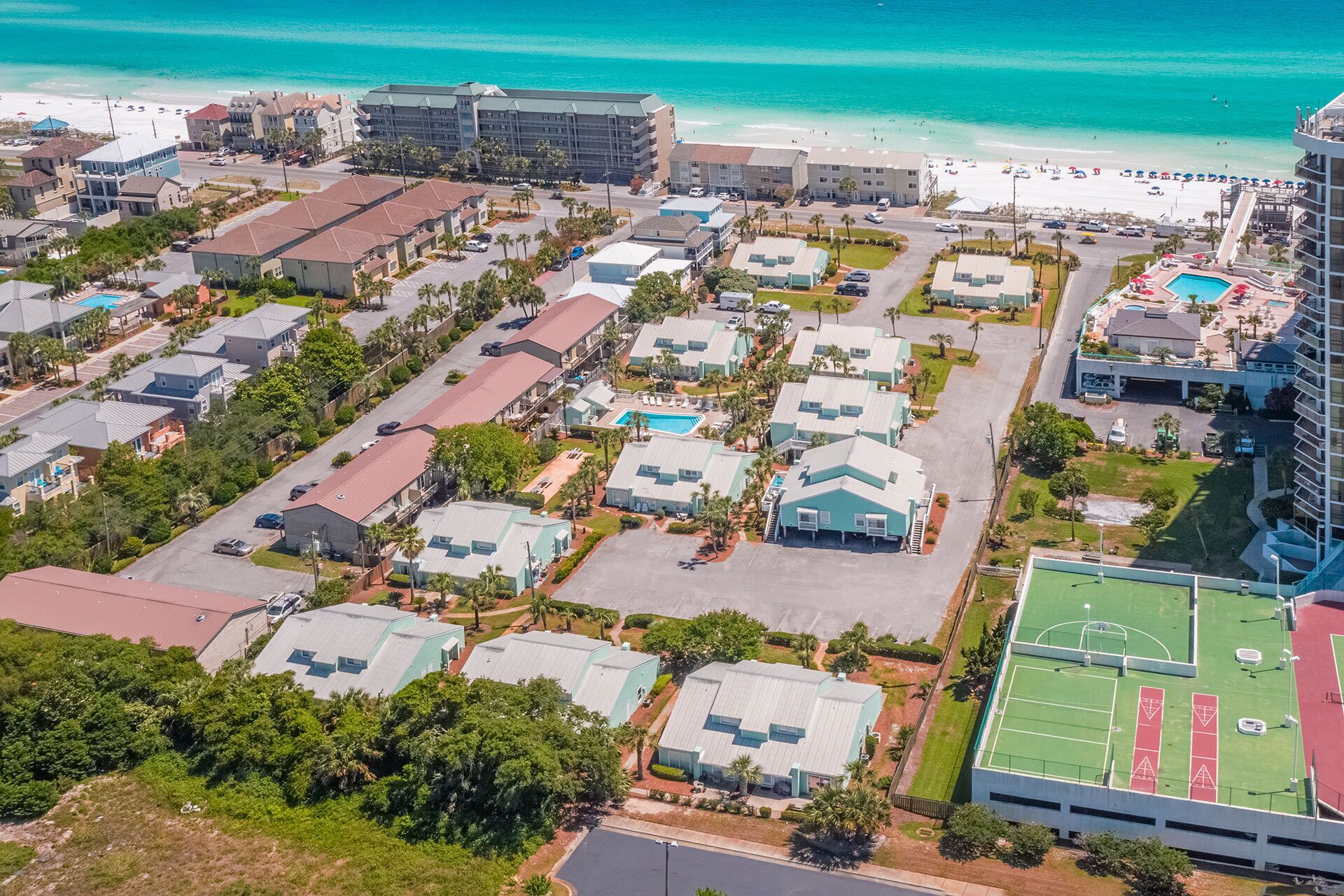 Una zona residencial costera con varias casas de dos pisos, una playa y un hotel.