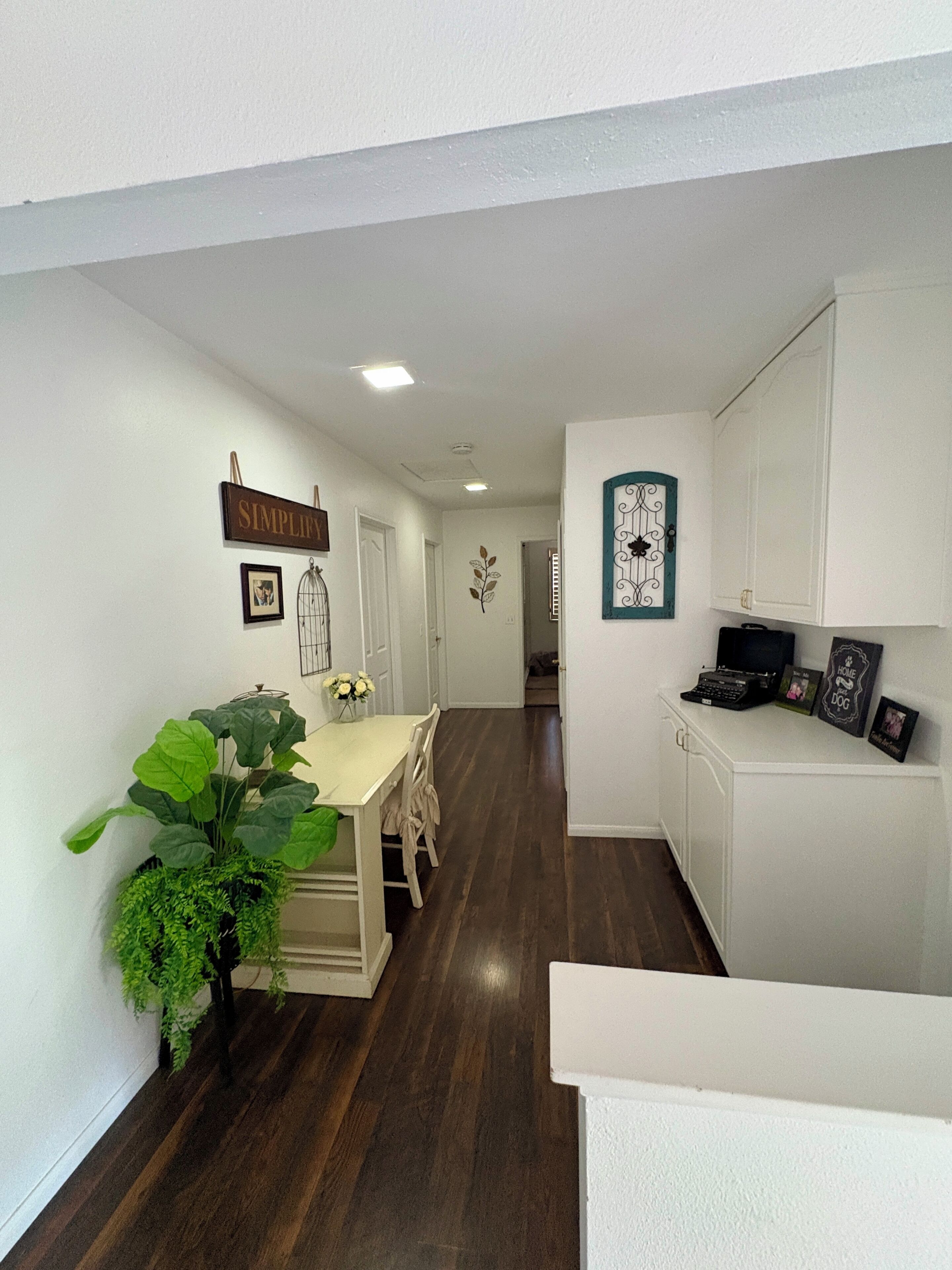 A hallway with a dining area, a white cabinet, and a plant.