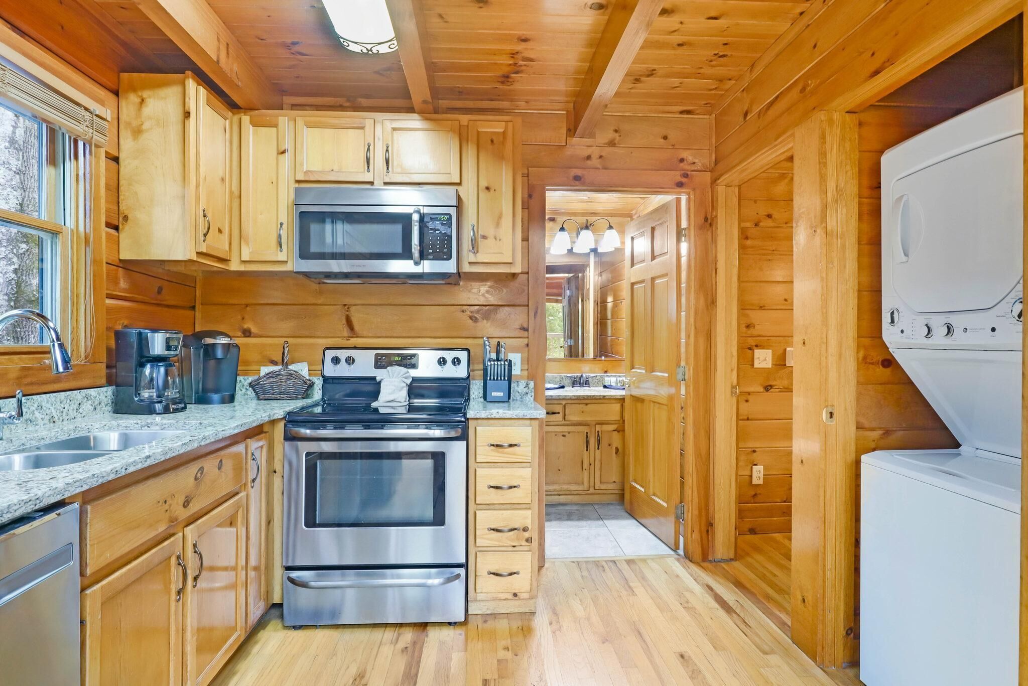 A wooden cabin kitchen with a stainless steel stove, microwave, and refrigerator.