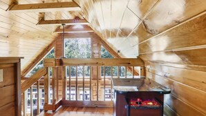 Ein Holzinnenraum mit einer Holztreppe, einem Billardtisch und Blick durch ein Fenster.
