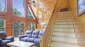 Ein Holzblockbau-Innenraum mit Treppe, großen Fenstern und einer Couch.