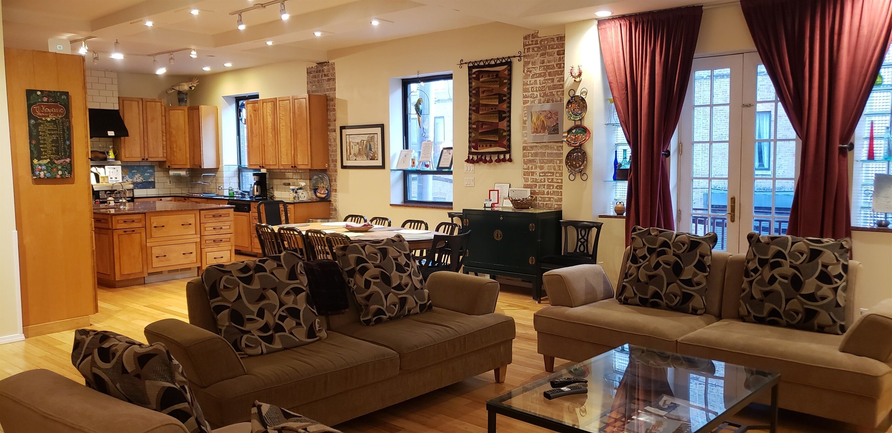 Ein gemütliches Wohnzimmer mit einer Sofagarnitur, einem Couchtisch und einem Essbereich mit Holzausbau sowie einer Küche im Hintergrund.