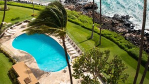 Una piscina circondata da palme con vista sull'oceano.