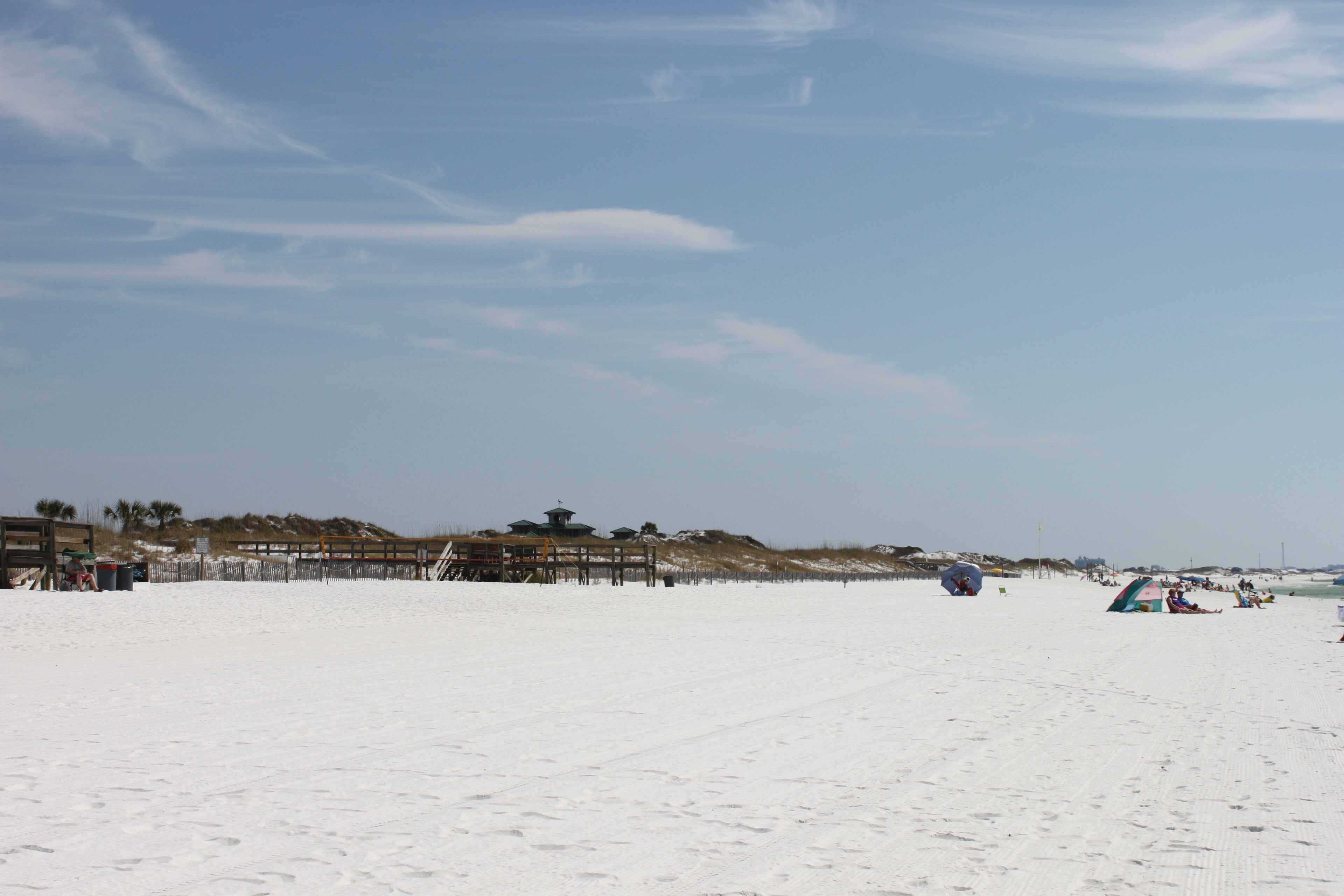 A beach with a wooden pier, a small building, and a tent.
