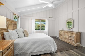 Un dormitorio con cama, cómoda, espejo y ventana con contraventanas.
